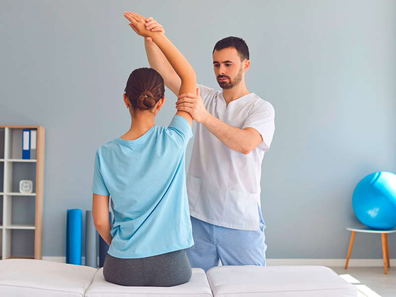 Manuelle Therapie in Mainz mit gezielten Grifftechniken zur Mobilisation der Arm- und Schultergelenke einer Patientin.