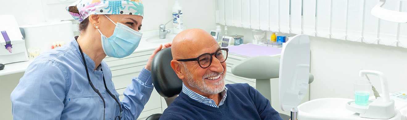 Zahnarzthelferin erklärt Seniorpatient Behandlungsergebnis nach erfolgreicher Oralchirurgie in Mainz in moderner Zahnarztpraxis mit persönlicher Beratung und zufriedener Atmosphäre.