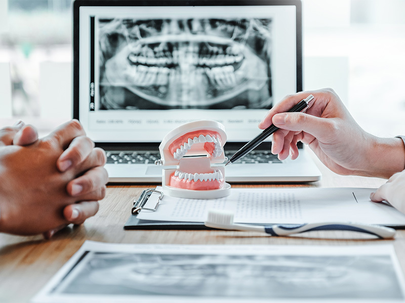 Zahnarzt bespricht mit männlichem Patienten Röntgenaufnahme zur Behandlungsplanung in der Oralchirurgie in Mainz in moderner Praxis.