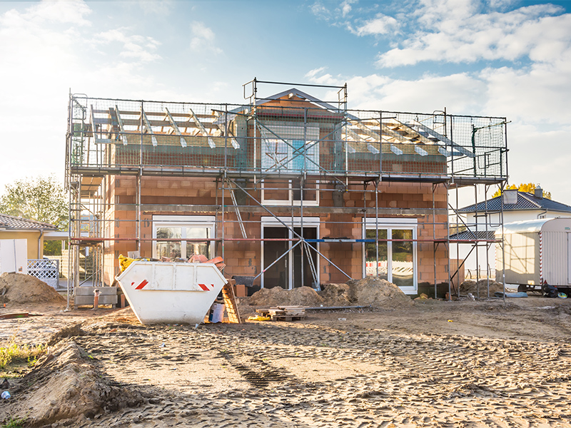 Rohbau in Rüsselsheim eines Einfamilienhauses mit Mauerwerk, Dachkonstruktion und Gerüst bei sonnigem Wetter während der Bauphase.